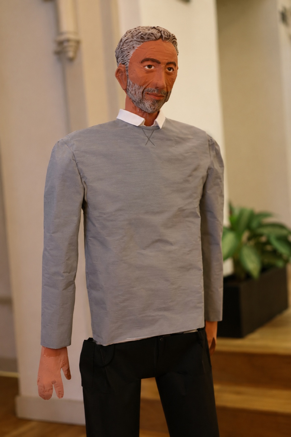 A standing Amol statue wearing a gray shirt